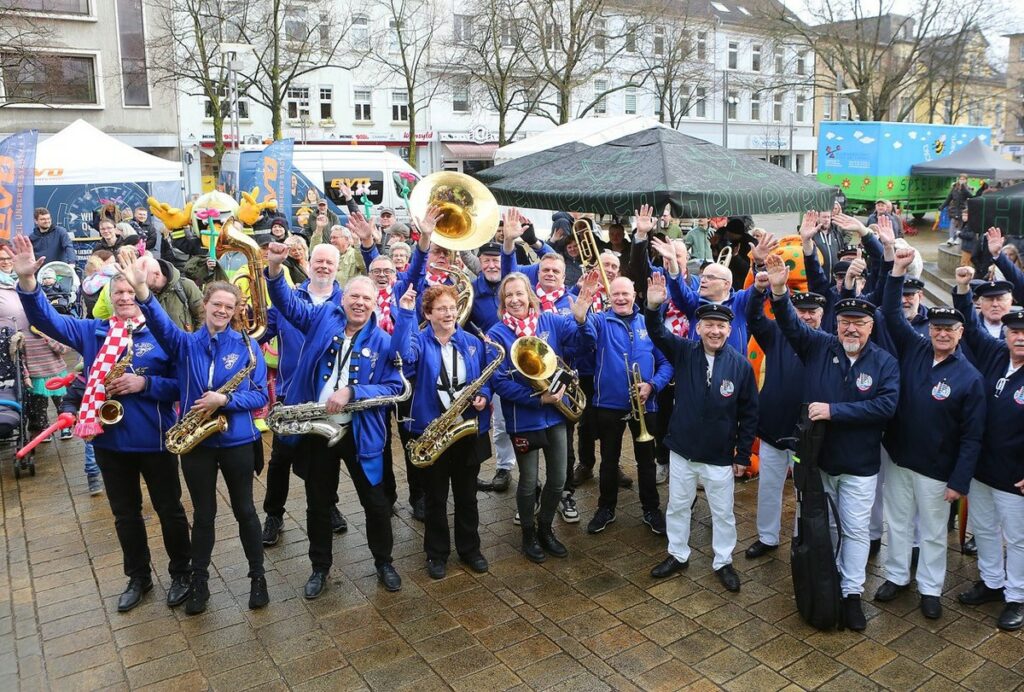 Band ist gut gelaunt beim Cityfest, Mitglieder halten diverse Instrumente und winken in die Kamera